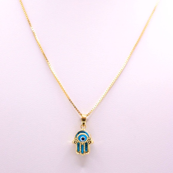 Hamsa pendant with a blue stone paired with a necklace. - Picture 2 of 3
